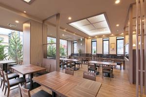 Hotel Route Inn Grand Nakano Obuse في Nakano: مطعم بطاولات وكراسي خشبية ونوافذ