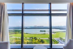 a room with a large window looking out at a lake at Cordis, Xuzhou in Xuzhou