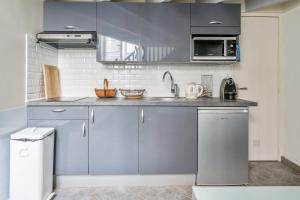 Charming duplex near Paris - Welkeys في بولون بيانكور: مطبخ مع دواليب زرقاء ومغسلة
