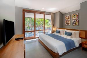 a bedroom with a large bed and a television at Ecozy Dijiwa Canggu in Canggu