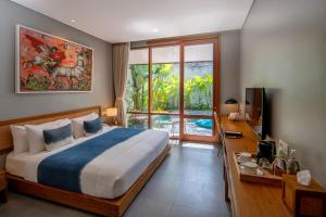 a bedroom with a bed and a desk and a television at Ecozy Dijiwa Canggu in Canggu