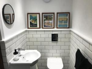 une salle de bain avec un lavabo et des toilettes et trois tableaux dans l'établissement Hunters Cottage, à Bakewell 22 autres photos