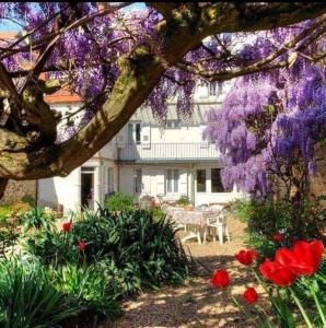 a garden with red and purple flowers and a house at H&ocirc;tel De La Fert&eacute; in Chagny