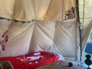 a tent with a red bed in front of it at Tipis La Paix retrouvée in Tourrette-Levens