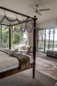 um quarto com uma cama de dossel e uma grande janela em Huge house Your Hunter Valley Wine Staycation ! em Pokolbin