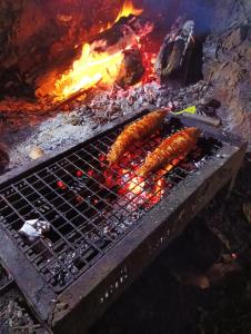 two sausages cooking on a grill with a fire at Nature river camp in Madikeri
