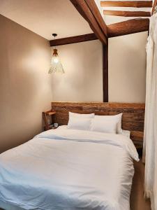 a bedroom with a large white bed with a wooden headboard at Relax House in Gyeongju