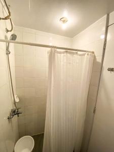 a bathroom with a shower with a white shower curtain at Kavanah Suites Guinhawa Tagaytay in Tagaytay