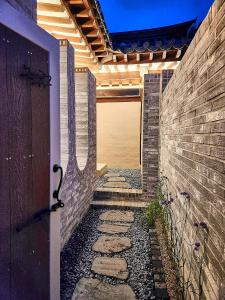 a walkway with a brick wall and a wooden door at Relax House in Gyeongju