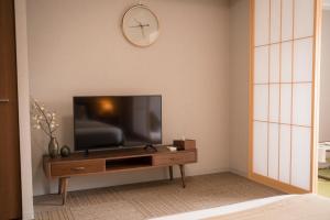 uma sala de estar com uma televisão de ecrã plano numa mesa de madeira em 川House道頓堀 em Osaka