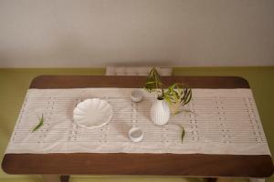 川House道頓堀 في أوساكا: طاولة عليها صحون و مزهريات بيضاء