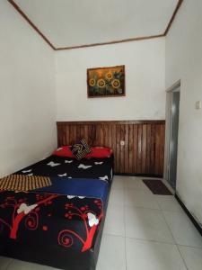 Senduro的住宿－Bali Ciliek Homestay，卧室配有一张床,墙上挂有绘画作品