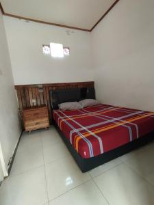 Senduro的住宿－Bali Ciliek Homestay，一间卧室配有一张带红色和橙色条纹毯子的床