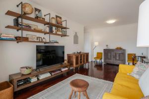 ein Wohnzimmer mit einem gelben Sofa und einem TV in der Unterkunft Funchal bay view Vista Mar I in Funchal