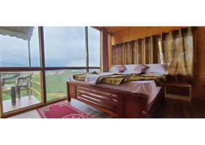 een bed in een kamer met een groot raam bij The Legian 4 BHK in Ooty