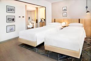 two beds in a hotel room with a mirror at Sheraton Abu Dhabi Hotel & Resort in Abu Dhabi