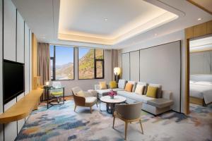 ein Hotelzimmer mit einem Sofa und einem Bett in der Unterkunft Hilton Garden Inn Nujiang in Lushui