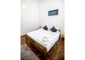 1 dormitorio con 1 cama con sábanas blancas y mesa en Villa Evora, en Ooty