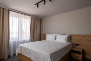 BET25 Hotel في باتومي: غرفة نوم بسرير وملاءات بيضاء ونافذة