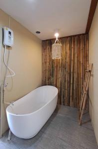 uma banheira branca na casa de banho com uma parede de madeira em U're Holitel em Haad Rin