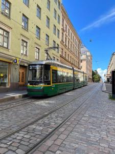 赫爾辛基的住宿－Design stay in the heart of Punavuori，一条绿色和黄色的电车在城市街道上