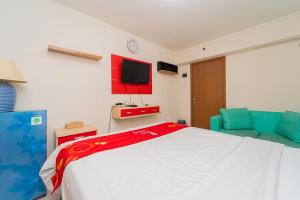 ein Schlafzimmer mit einem Bett und einem Fernseher an der Wand in der Unterkunft RedLiving Apartemen Cinere Resort - Gold Room in Gandul