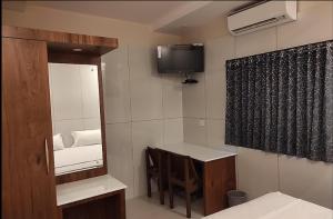 Zimmer mit einem Tisch, einem Spiegel und einem TV in der Unterkunft QUILON RESIDENCY KOLLAM in Kollam
