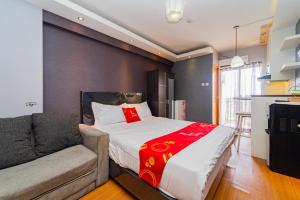 ein Schlafzimmer mit einem Bett und einer Couch in der Unterkunft RedLiving Apartemen Cinere Resort - Gold Room in Gandul + 42 Fotos