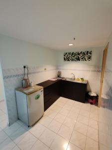 a small kitchen with a refrigerator and a sink at 2 mins to beach Apartment 3 rooms in Pasir Bogak