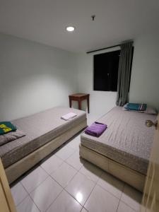 a bedroom with two beds and a tv on the wall at 2 mins to beach Apartment 3 rooms in Pasir Bogak