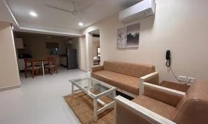 uma sala de estar com um sofá e uma mesa de vidro em FabHotel Prime AM Suites Near Yashoda Hospital em Hyderabad