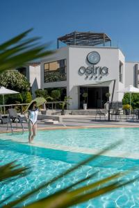 una mujer con una tabla de surf en una piscina en Ostria Sea Side Hotel en Hanioti