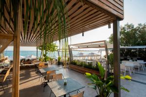 an outdoor patio with tables and chairs and the ocean at Ostria Sea Side Hotel in Hanioti