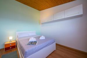 una piccola camera da letto con un letto con un libro sopra di Petit Cadeau - Happy Rentals a Cademario