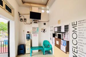 Zimmer mit 2 Stühlen und einem TV an der Wand in der Unterkunft RedDoorz At Damai Guest House Kabanjahe in Kabanjahe