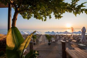 a boardwalk with chairs and a beach at sunset at Ostria Sea Side Hotel in Hanioti