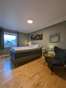 a bedroom with a bed and a chair and a window at Sea & Mountain View Apartment Tromsø in Tromsø