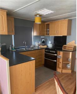 uma cozinha com armários de madeira e um balcão preto em Family or couple 3-bed cosy home with fireplace, 50 deposit required, self-catering em Hastings