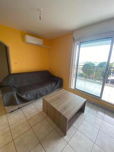 a living room with a couch and a large window at Appartement F2 centre-ville Saint-André in Saint-André