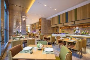 un restaurante con mesas y sillas de madera y un chef en Hilton Garden Inn Nujiang, en Lushui