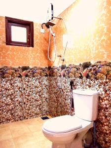 a bathroom with a toilet in a room with a wall at Sol Y Mar - Unawatuna in Galle