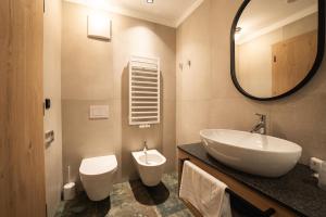 een badkamer met een wastafel, een toilet en een spiegel bij Aparthotel Zum Schlössl in Villa Ottone