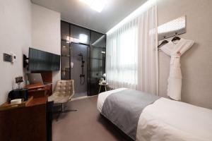 ソウルにあるHotel DMのベッド、デスク、窓が備わるホテルルームです。