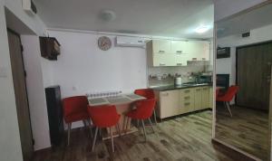 a kitchen with a table and red chairs in a room at Regim hotelier Alba Iulia AmOS in Alba Iulia