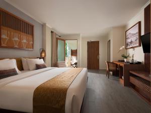 um quarto de hotel com uma cama grande e uma secretária em Anantara Vacation Club Legian em Legian