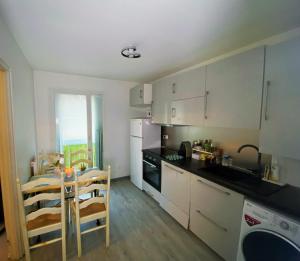 a kitchen with white cabinets and a table and chairs at Cosy Roissy for Olympic Games in Roissy-en-France