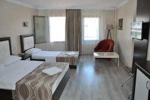 a hotel room with two beds and a chair at Konak EuroBest Otel in Konak