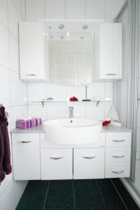 a white bathroom with a sink and a mirror at Ferienhaus Pelikanstr 82 Ostermann Bungalow 3 in Norddeich