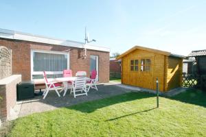 Ferienhaus Pelikanstr 129 Ostermann Bungalow 5 في نورديش: حديقة خلفية بها طاولة وكراسي وسقف