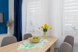 a dining room table with a bowl of fruit and flowers on it at Apartament nad Jeziorem Kołczewo - Ogród & Parking by Renters in Kołczewo